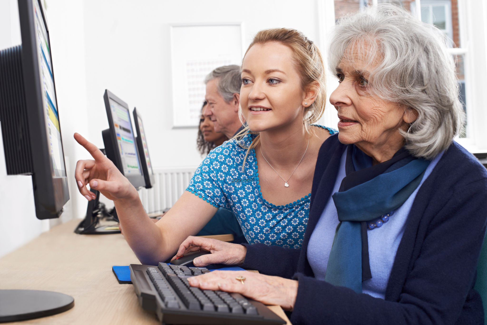 Foto zum Projekt Digitales Dorf Senioren; Junge Frau, die einer älteren Frau am PC hilft