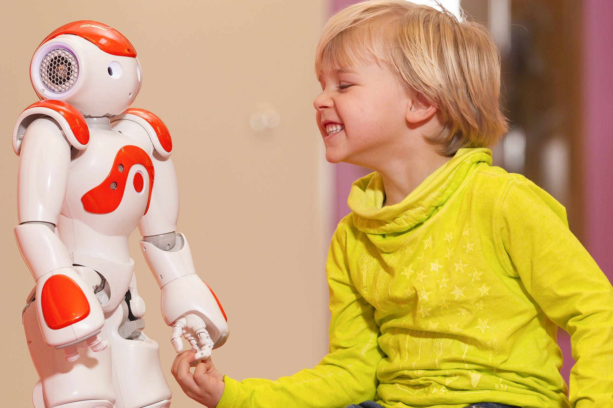 Forschungsprojekt ERIK, lachendes Kind spielt mit Roboter